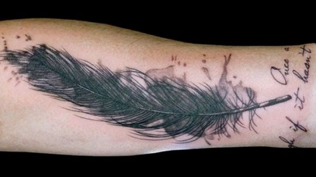 Brazo con una pluma tatuada